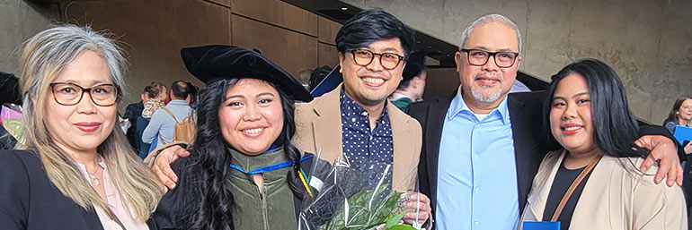 A graduate stands with family members after commencement.