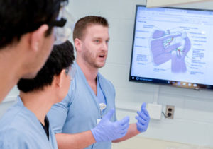 A NEOMED faculty member makes a point to Anatomy Academy students in a lab.