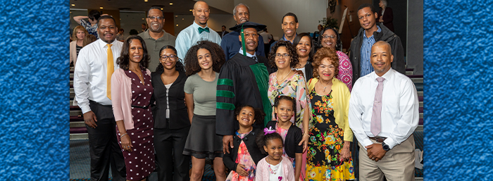 Photo of African American man in medical school regalia posing with family and friends.