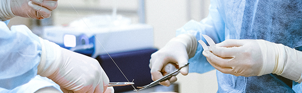 hands using surgical scissors to cut suture thread