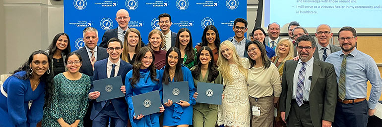 A group of about 20 medical students and faculty members pose as a group.