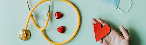 Yellow stethoscope, disposable face covering and three red hearts