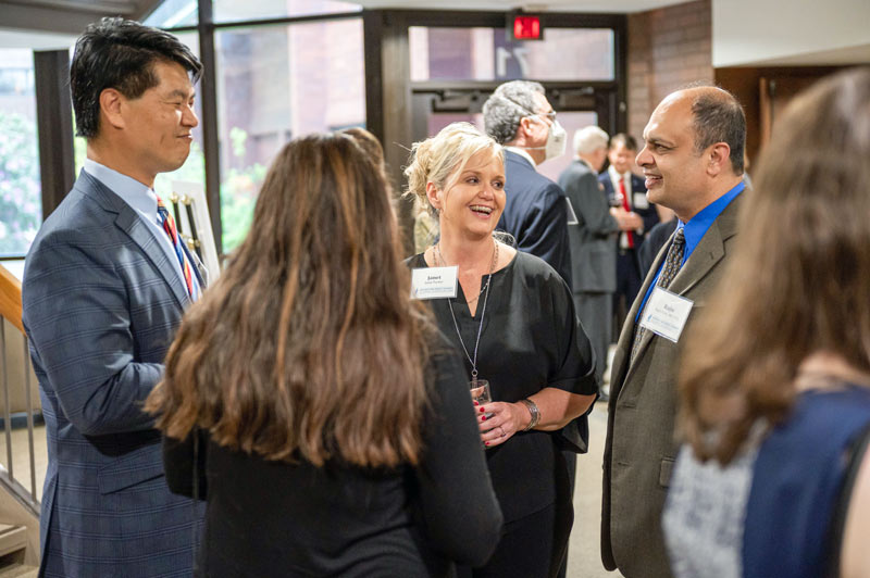 Four alumni smile while engaging in conversation.