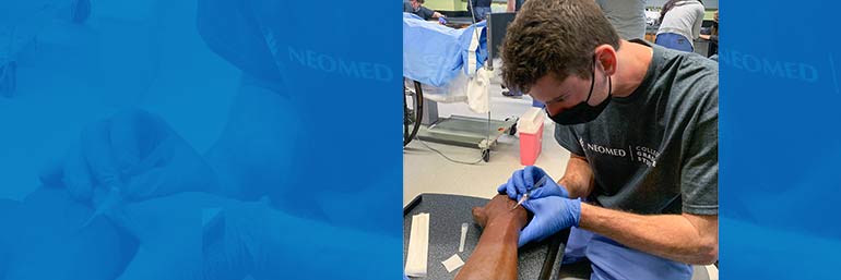 A student administers an IV in a laboratory.