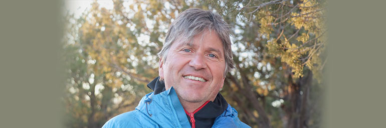 A man in a coat outdoors on a fall afternoon.