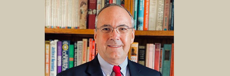 NEOMED's first provost, C. Forrest Faison, stands before a bookcase.