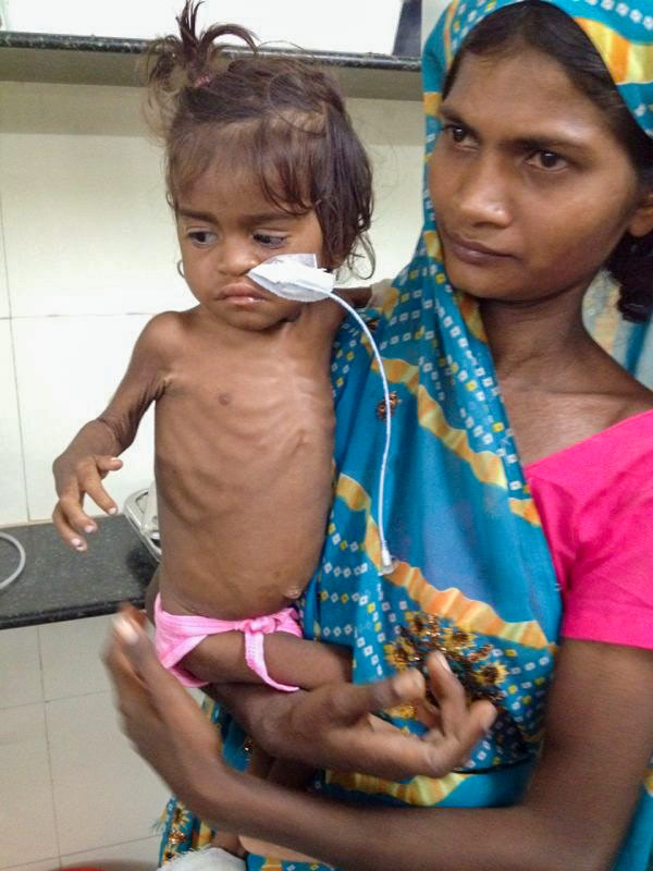 A mother holds her daughter, who is receiving oxygen.