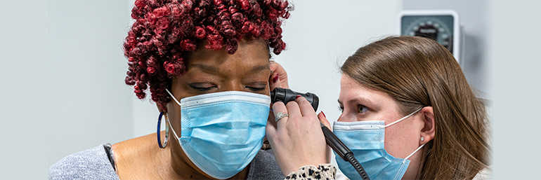 A physician checks the ear of a patient.